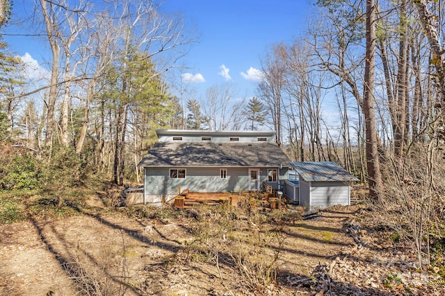 back of house with an outdoor structure and a shed