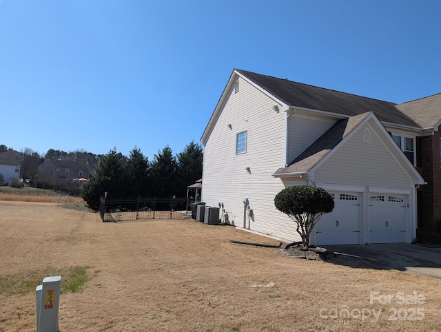 view of side of property with driveway, central AC, and fence