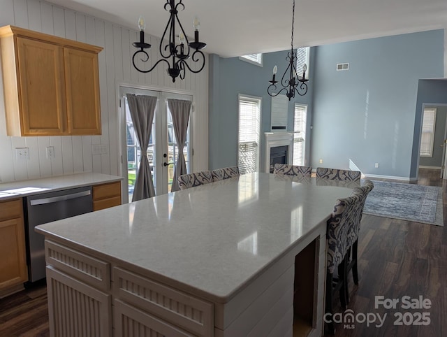 kitchen with dishwasher, dark wood-style flooring, a kitchen bar, a chandelier, and a fireplace