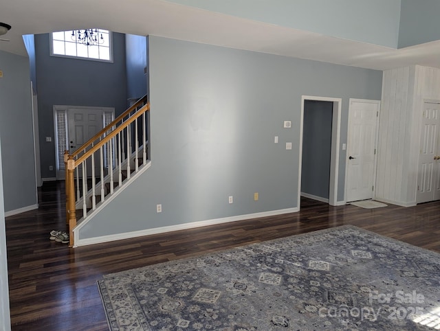 interior space featuring stairs, a chandelier, wood finished floors, and baseboards