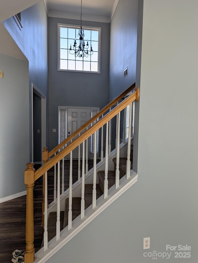 staircase featuring ornamental molding, visible vents, and a towering ceiling