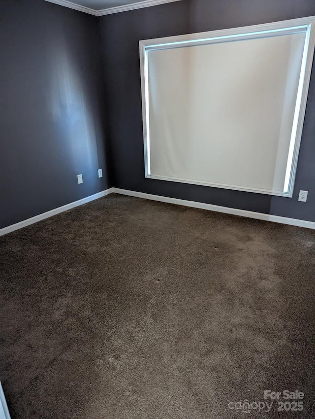 spare room with ornamental molding, dark colored carpet, and baseboards