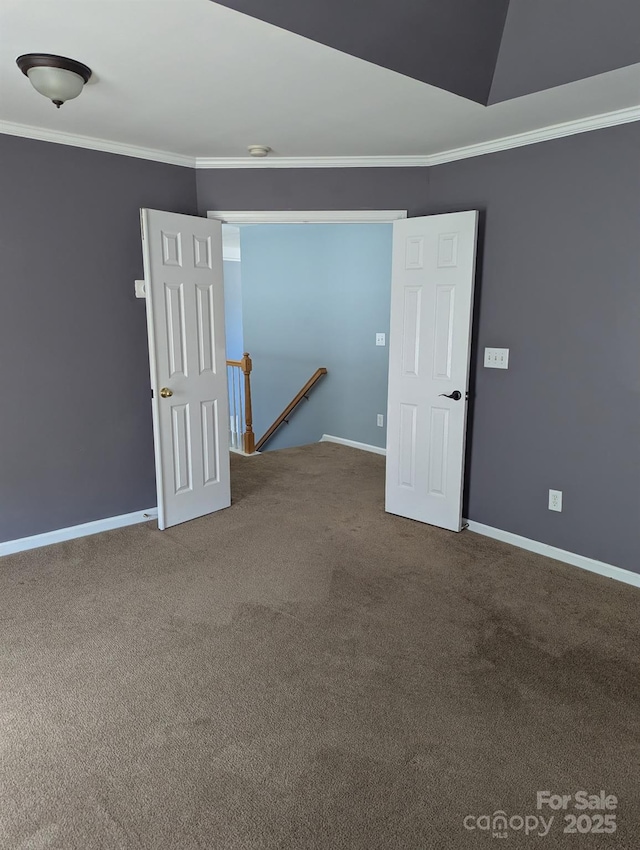 carpeted empty room featuring baseboards and crown molding