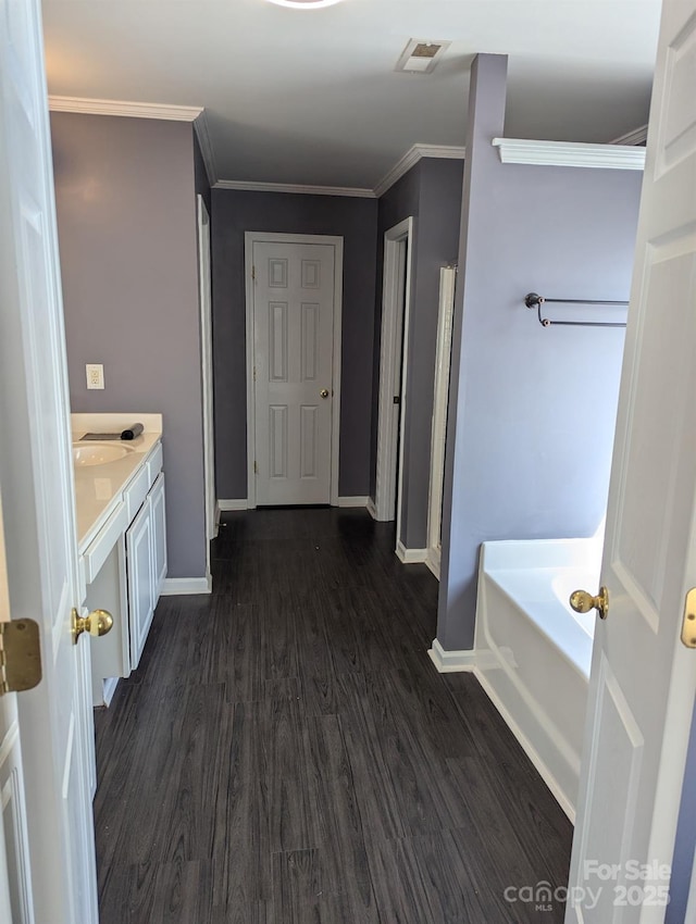 bathroom with a garden tub, wood finished floors, visible vents, baseboards, and crown molding