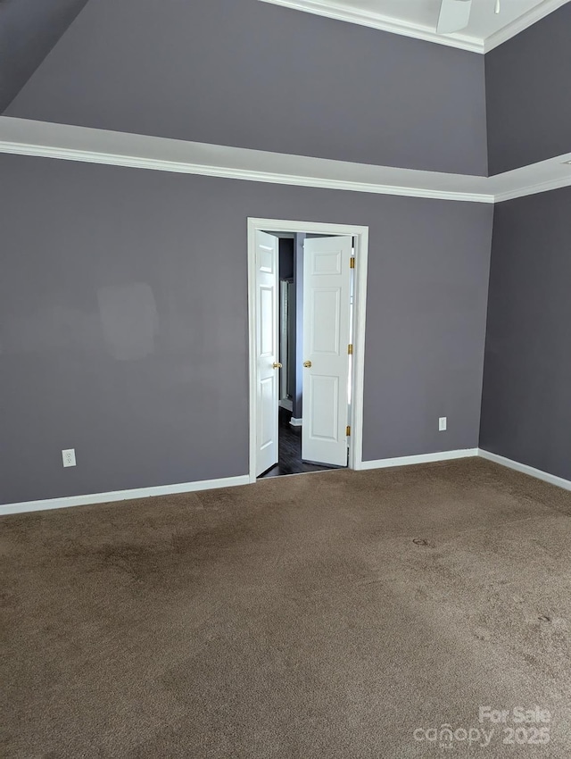 spare room with ornamental molding, dark carpet, and baseboards