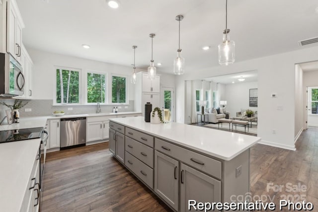 kitchen featuring dark wood-type flooring, white cabinetry, visible vents, appliances with stainless steel finishes, and a center island