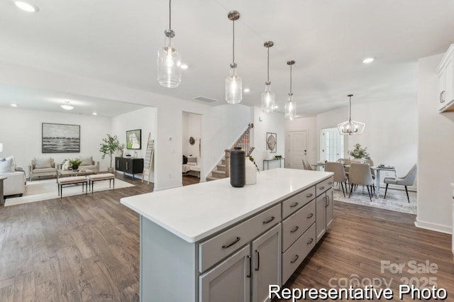 kitchen featuring a kitchen island, open floor plan, light countertops, gray cabinets, and dark wood finished floors