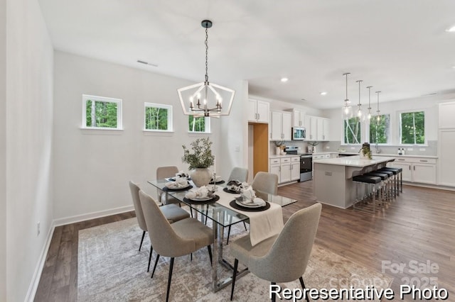 dining space with a chandelier, recessed lighting, baseboards, and wood finished floors