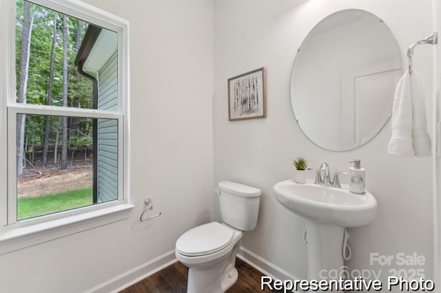 bathroom with wood finished floors, toilet, and baseboards