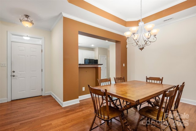 dining area with visible vents, baseboards, a chandelier, light wood-type flooring, and ornamental molding