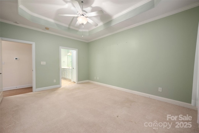 unfurnished bedroom with a raised ceiling, ornamental molding, baseboards, and light carpet