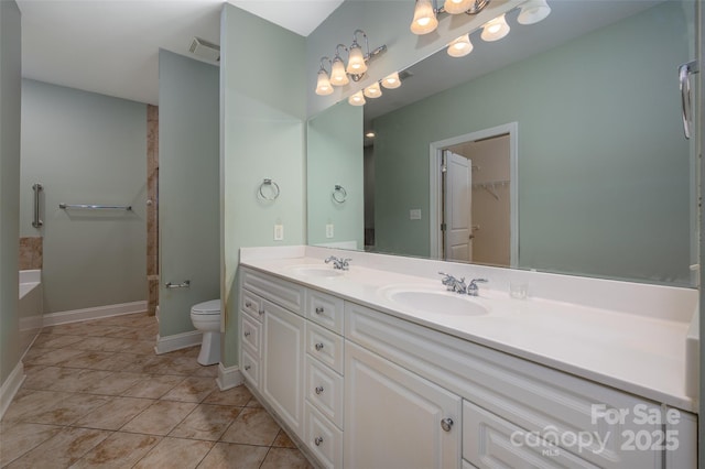 full bathroom with double vanity, tile patterned flooring, toilet, and a sink