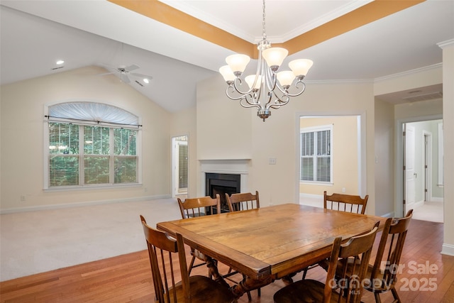 dining area with ornamental molding, ceiling fan with notable chandelier, wood finished floors, a fireplace, and baseboards