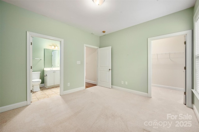 unfurnished bedroom with baseboards, a walk in closet, carpet floors, and a closet