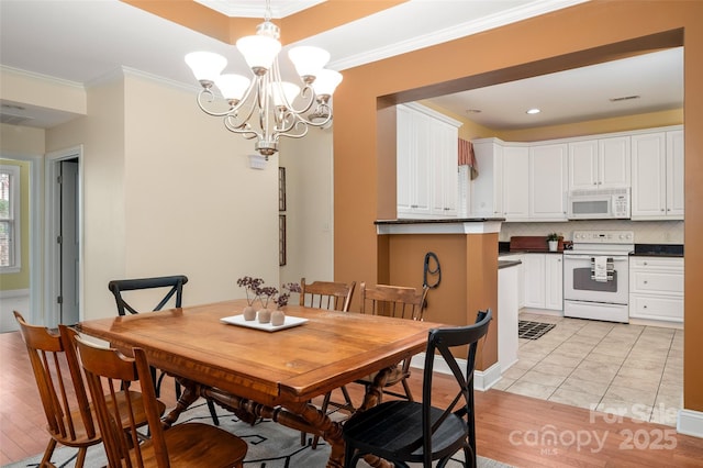 dining room with light wood-style flooring, visible vents, a chandelier, and ornamental molding