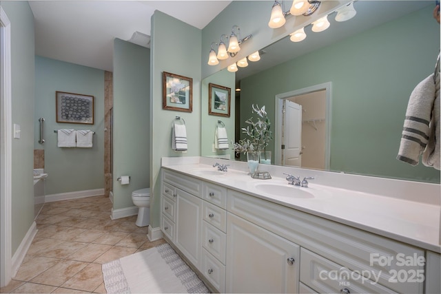 bathroom with a sink, toilet, double vanity, and tile patterned flooring