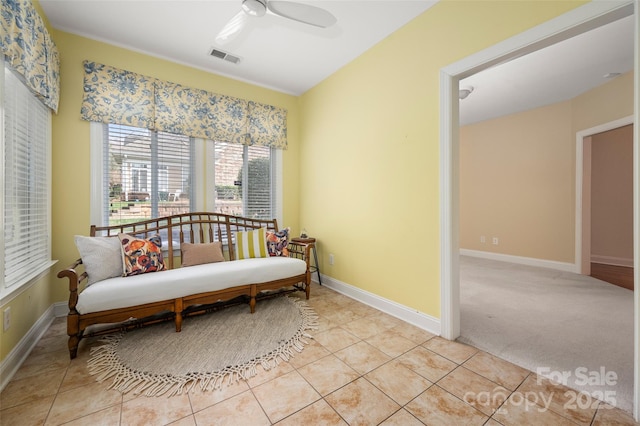 living area with visible vents, baseboards, light colored carpet, light tile patterned flooring, and a ceiling fan