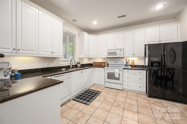 kitchen with white appliances, backsplash, white cabinets, and a sink