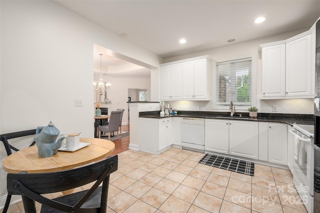 kitchen featuring a wealth of natural light, white appliances, backsplash, and a sink