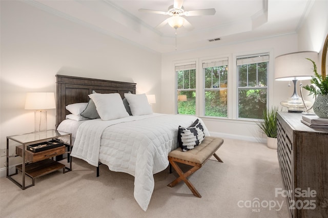 bedroom with light colored carpet, a raised ceiling, visible vents, baseboards, and ornamental molding