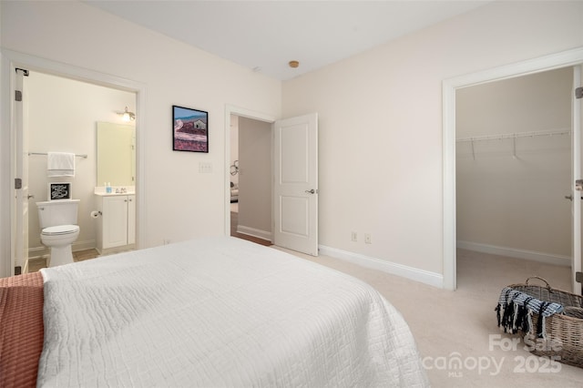 bedroom featuring carpet floors, connected bathroom, a closet, baseboards, and a spacious closet