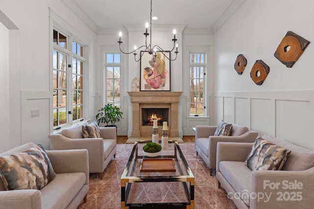 living room with a fireplace, crown molding, a notable chandelier, and a healthy amount of sunlight