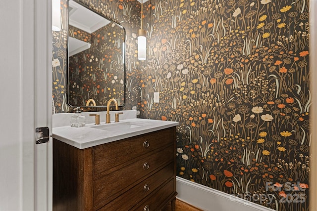 bathroom with ornamental molding, vanity, and wallpapered walls