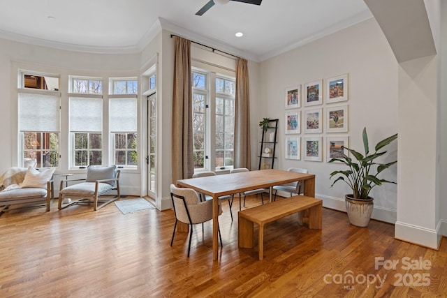 dining room featuring ceiling fan, baseboards, light wood-style flooring, and crown molding