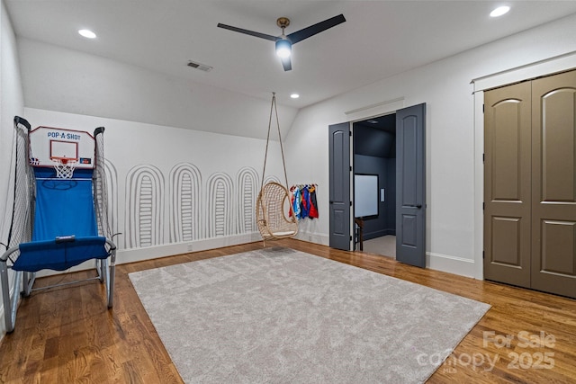 interior space with a ceiling fan, lofted ceiling, wood finished floors, and visible vents