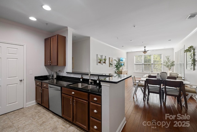 kitchen featuring visible vents, dishwasher, dark countertops, a peninsula, and a sink