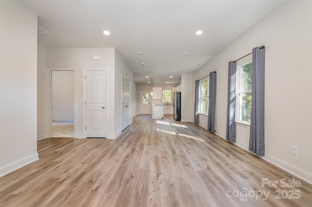 unfurnished living room with light wood finished floors, baseboards, and recessed lighting