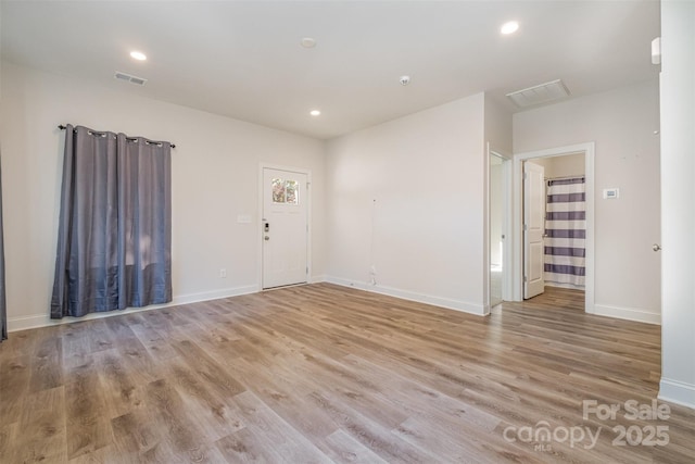 empty room featuring light wood-type flooring, visible vents, baseboards, and recessed lighting