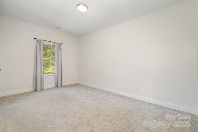 spare room featuring light carpet, visible vents, and baseboards