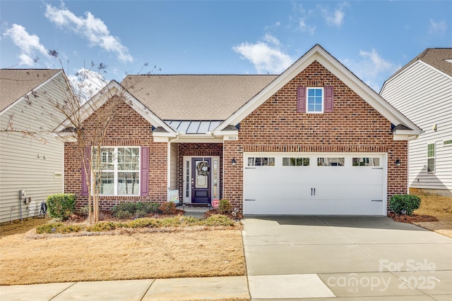 view of front facade with a standing seam roof, brick siding, driveway, and an attached garage