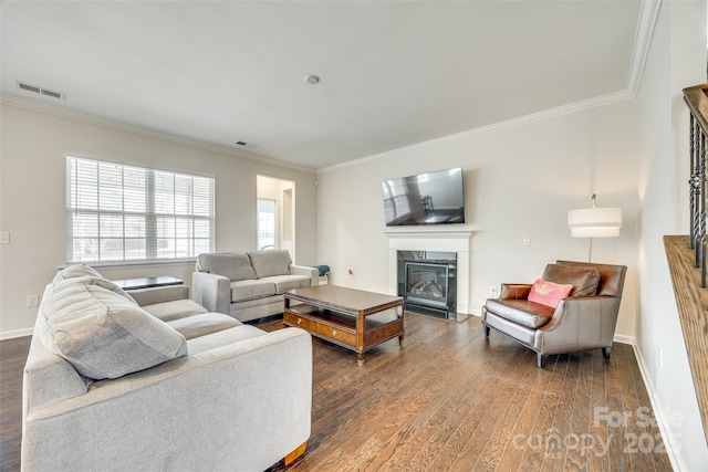 living area with baseboards, visible vents, a fireplace with flush hearth, ornamental molding, and dark wood-type flooring