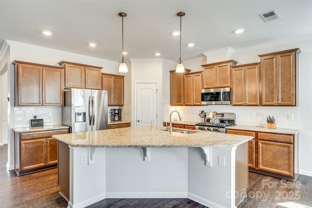 kitchen featuring stainless steel appliances, brown cabinetry, a sink, and dark wood finished floors