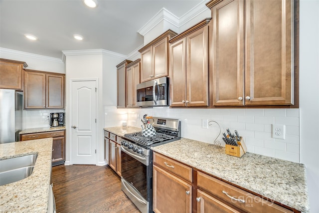 kitchen featuring light stone counters, appliances with stainless steel finishes, decorative backsplash, dark wood finished floors, and crown molding