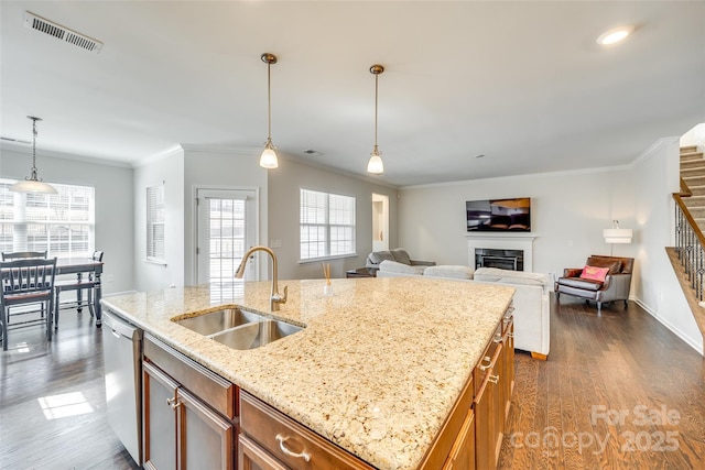 kitchen featuring a fireplace, visible vents, brown cabinetry, a sink, and dishwashing machine