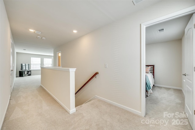 hall featuring recessed lighting, light colored carpet, visible vents, baseboards, and an upstairs landing