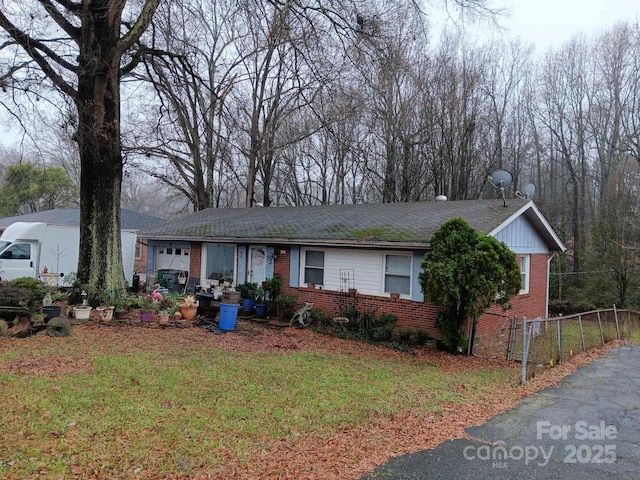 ranch-style house with an attached garage, fence, a front lawn, and brick siding