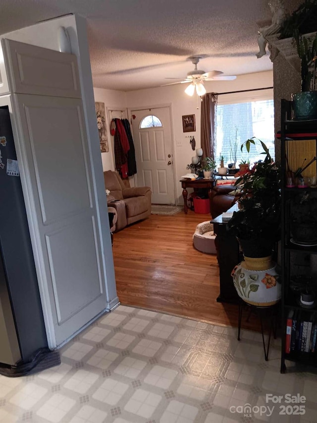 entryway with light floors, ceiling fan, and a textured ceiling