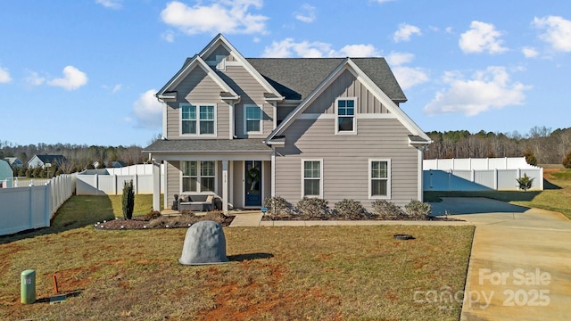 view of front of home featuring driveway, a shingled roof, fence private yard, a front lawn, and board and batten siding