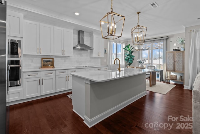 kitchen featuring white cabinets, decorative light fixtures, stainless steel oven, and wall chimney exhaust hood