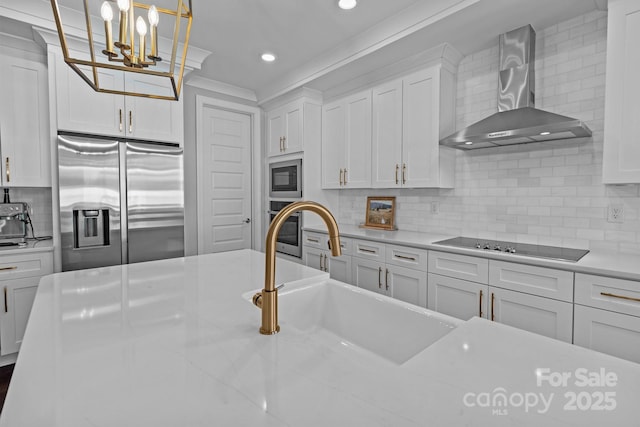 kitchen featuring wall chimney range hood, appliances with stainless steel finishes, white cabinets, and a sink