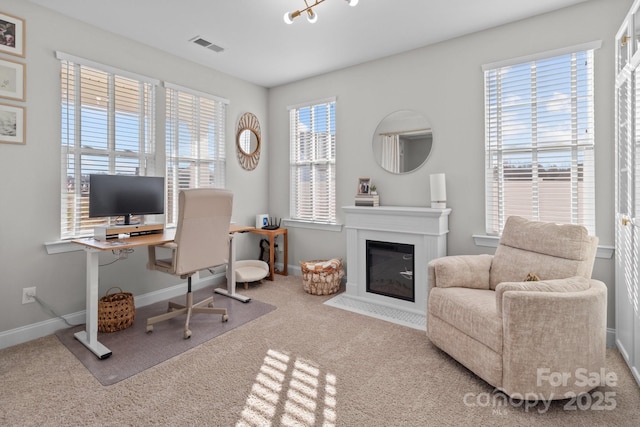 carpeted office featuring a fireplace with flush hearth, visible vents, and baseboards