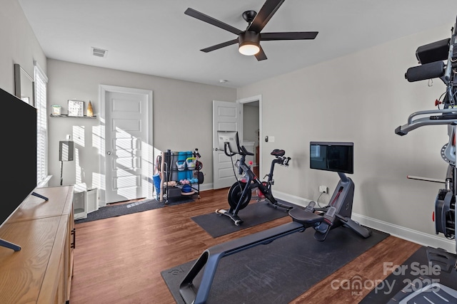 exercise room featuring baseboards, visible vents, ceiling fan, and wood finished floors