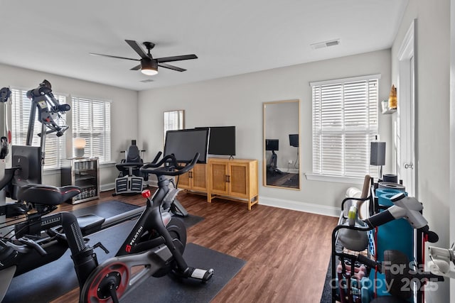 workout area featuring baseboards, dark wood-style flooring, visible vents, and a ceiling fan