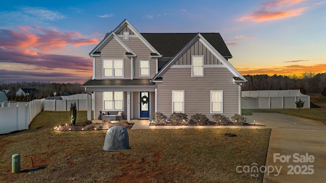 traditional-style home with board and batten siding, a front yard, fence, and driveway