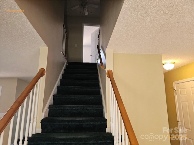 staircase featuring a textured ceiling and baseboards