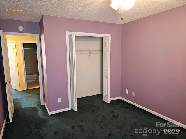 unfurnished bedroom with a textured ceiling, dark carpet, and baseboards